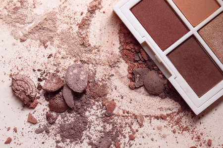 Crashed eyeshadows and eyeshadow palet. Macro texture of make-up on beige backgroundの写真素材