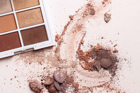 Crashed eyeshadows and eyeshadow palet. Macro texture of make-up on beige backgroundの写真素材