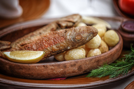 Grilled fish with roasted potatoes in stoneware dish