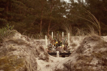 A table  designed for a boho style event with an eucalyptus, vintage plates and other rustic touches. On seaside in the sand dunesの写真素材