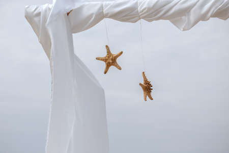 Bohemian wedding decor, two sea stars hanging on archの写真素材