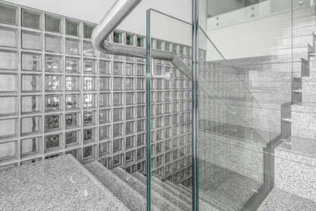 Transparent walls and staircase in modern building against wall with glass square tiles.の写真素材