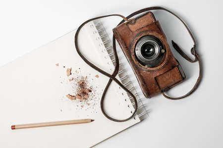 Notebook with brown pencil and old film camera on white backgroundの写真素材
