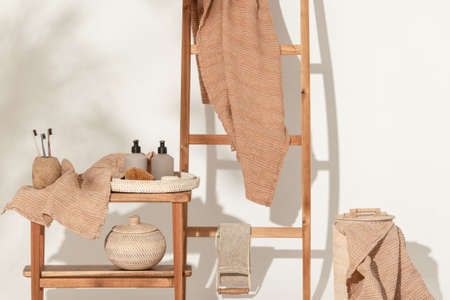 Natural waffle linen towels in earth tones on wood bench and towel ladder with bamboo toothbrushes, rattan baskets, and soap dispenser. Daily body care, spa and wellness zero waste bathroom conceptの写真素材
