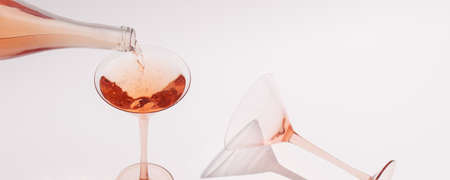 Pouring Rose wine in cocktail rose glass on white backgroundの写真素材
