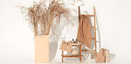 Natural waffle linen towels in earth tones on wood bench and towel ladder with bamboo toothbrushes, rattan baskets, and soap dispenser. Daily body care, spa and wellness zero waste bathroom conceptの写真素材