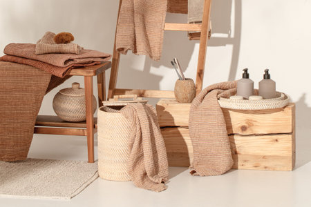 Natural waffle linen towels in earth tones on wood bench and towel ladder with bamboo toothbrushes, rattan baskets, and soap dispenser. Daily body care, spa and wellness zero waste bathroom conceptの写真素材
