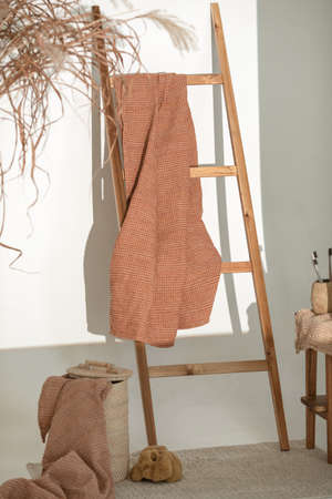 Natural waffle linen towels in earth tones on wood bench and towel ladder with bamboo toothbrushes, rattan baskets, and soap dispenser. Daily body care, spa and wellness zero waste bathroom conceptの写真素材