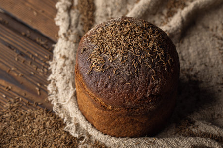Round loaf of rye bread with thyme on rustic style wooden table