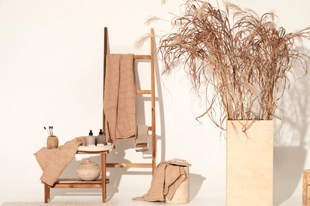 Natural waffle linen towels in earth tones on wood bench and towel ladder with bamboo toothbrushes, rattan baskets, and soap dispenser. Daily body care, spa and wellness zero waste bathroom conceptの写真素材