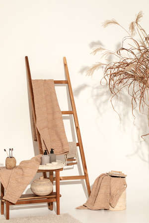 Natural waffle linen towels in earth tones on wood bench and towel ladder with bamboo toothbrushes, rattan baskets, and soap dispenser. Daily body care, spa and wellness zero waste bathroom conceptの写真素材