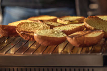 Process of cooking cheeseburgers on the grill.  Row of buns on the metal gridの写真素材