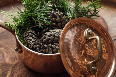Pine cones in copper small pot on solid wood board as decoration for holidaysの写真素材