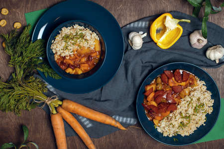Pilaf bowl (plov, pilaw, pilau) on dark blue bowls decorated with ingridents on wood table top view. Traditional middle east cuisine. Uzbekistan dish made of rice, beef , spices, carrot, onion and garlic.の写真素材