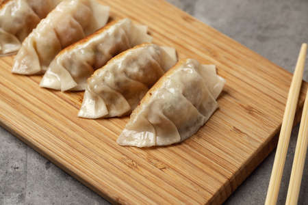 Gyoza or dumplings snack with soy sauce on wood board and grey clay backgroundの写真素材
