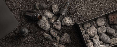 Essential oil for aromatherapy and mineral diffuser with volcanic stones in iron metal box on black sand  background. Aromatherapy, spa, beauty treatment and wellness concept.の写真素材
