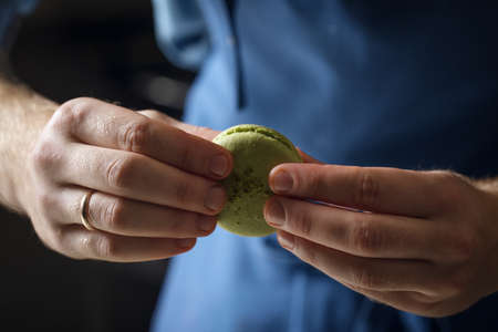 Pastry chef is holding two halves of macaroons. Close-up. The process of making dessert. Selective focus.の写真素材