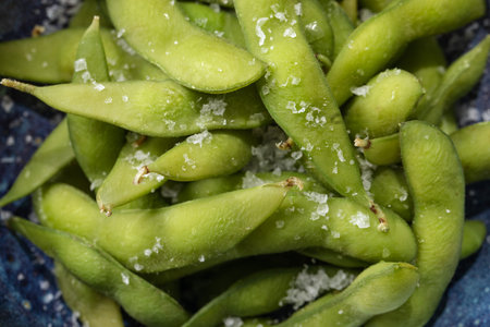 Organic steamed Japanese Edamame, a young soybean that is rich in nutrients served in blue bowl  and...