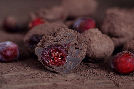 Homemade organic Cranberry truffles made of dark chocolate and frozen berries on solid oak table. Vegan truffles for healthy dessert.の写真素材