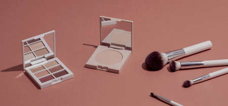 Pastel Eye shadow palette, highlighting powder and makeup brushes on pink background.の写真素材