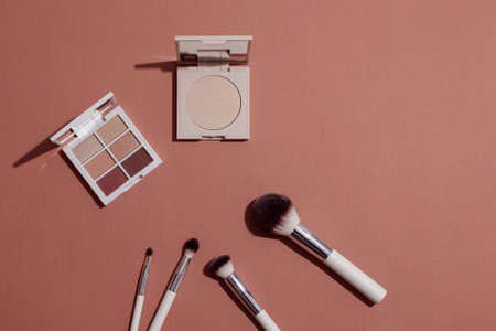 Pastel Eye shadow palette, highlighting powder and makeup brushes on pink background.の写真素材