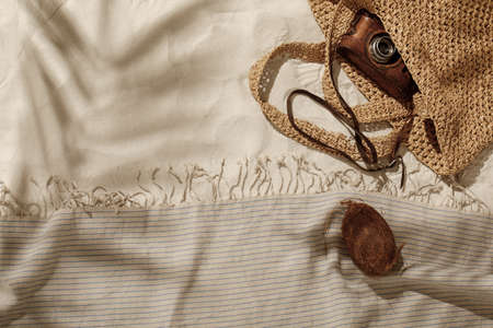 Striped linen beach towel with fringes, woven bag, vintage camera and coconut on sandy beach with shadows from palm tree. Relaxation and tropical summer holidays conceptの写真素材