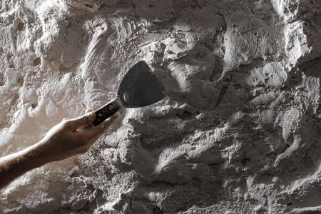 Process of creating white textured clay wall with cracks and imperfections using palette knife. Wall design ideas in contemporary interior.の写真素材