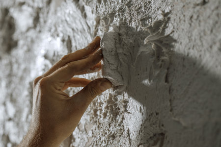 Process of creating white textured clay wall with cracks and imperfections using sstones. Wall design ideas in contemporary interior.の写真素材