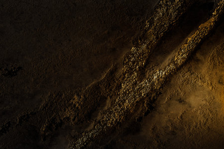 Grey concrete wall with shiny gold dust detail. Clay wall texture with cracks and imperfections....