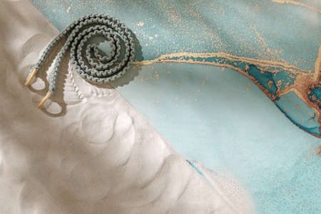 Unrolled ocean blue yoga mat and woven rope for stretching on sandy beach. Relaxation and meditation wellbeing and mindful living conceptの写真素材