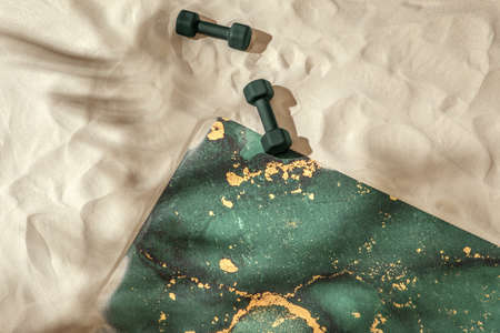 Unrolled green moss yoga mat and dumbbells on sandy beach. Relaxation and meditation wellbeing. Mindful living conceptの写真素材