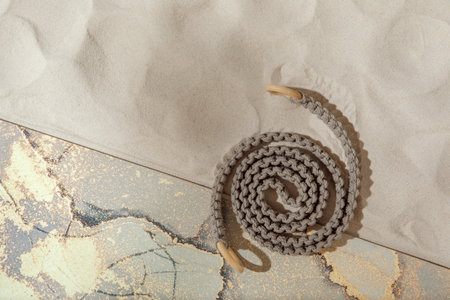 Unrolled  yoga mat and woven rope for stretching on sandy beach. Relaxation and meditation wellbeing...