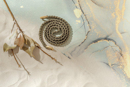Unrolled  yoga mat, woven rope for stretching and dried leaves on sandy beach. Relaxation and...