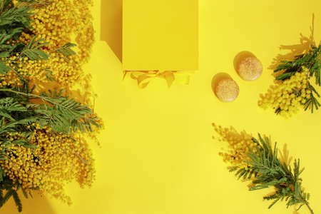 Branches of mimosa flowers, yellow macaroons and yellow gift box with ribbon bow. Greeting for International Womens Day on March 8, mothers day, Easter, Birthday or spring concept.の写真素材