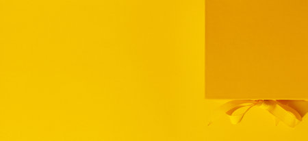 Bright yellow gift box with ribbon bow on yellow background top view copy space. Birthday present, March 8, Mothers Day, Valentines Day, Easter or spring concept.の写真素材