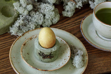 Table setting for Easter dinner decorated with forest moss, eggs coloured with matcha tea in moss green cement tray.の写真素材