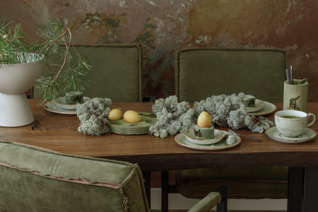 Table setting for Easter dinner decorated with forest moss, eggs coloured with matcha tea in moss...