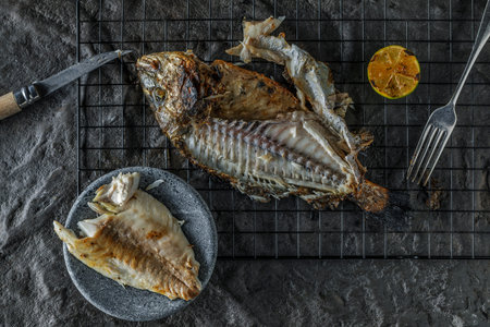 Whole grilled Dorado with grilled lime or Sea Bream on dark textured background. Healthy eating...