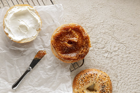 Freshly baked bagel with cream cheese and fig jam on baking paperの写真素材