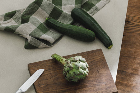 Zucchini and artichoke on wooden board, linen towel and stainless still kitchen knife. Healthy food cooking ingredients background with fresh vegetablesの写真素材
