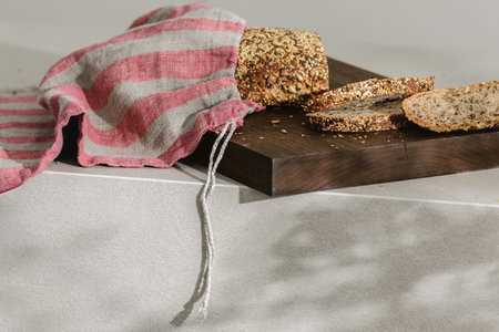 Sliced bread on wooden board in linen bag close up. Kitchen aesthetic concept