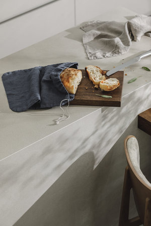 Sliced bread in linen bag on wooden board, fresh herbs and stainless kitchen knife.