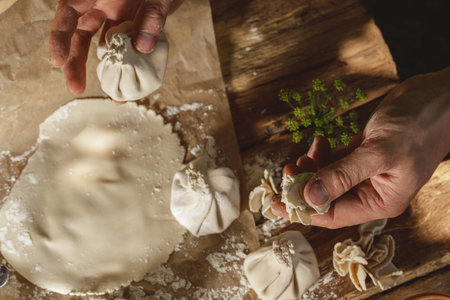 Hands expertly mold khinkali, the traditional Georgian dumplings, in bright sunlight, showcasing...