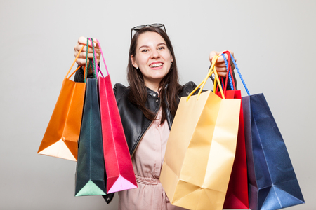 Beautiful laughing caucasian girl stretch out color shopping bagsの写真素材