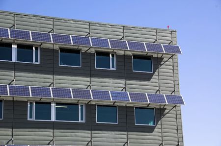 Super modern green office building utilizing the latest environmental technology. The Solar panels here do double duty and provide energy for electricity and shade over the windows to help lower ambient temperature within the building.の写真素材