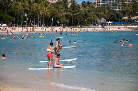 OAHU, HI - Tourist sunbathing and surfing on Waikiki beach June 26, 2013 in Oahu. Waikiki beach is beachfront neighborhood of Honolulu, best known for white sand and surfing.のeditorial素材