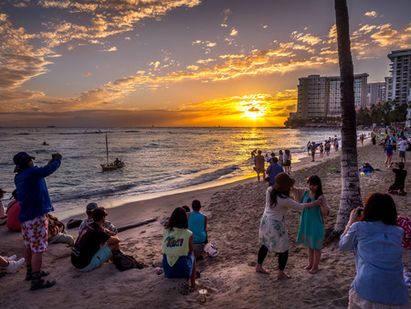 Tourists on the beach front at sunset on Waikiki beach April 27, 2014 in Oahu  Waikiki beach is beachfront neighborhood of Honolulu, best known for white sand and surfing  のeditorial素材