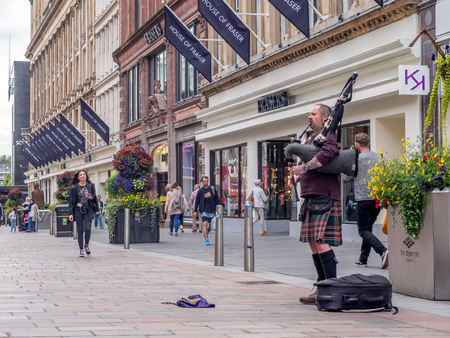 GLASGOW, SCOTLAND - JULY 21: A bagpiper on Buchanan Street on July 21, 2017 in Glasgow, Scotland. Buchanan Street is a popular tourist destination and so there is always a bagpiper busking for change.のeditorial素材