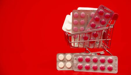 Shopping basket with medicines with space for your text on a red  backgroundの写真素材