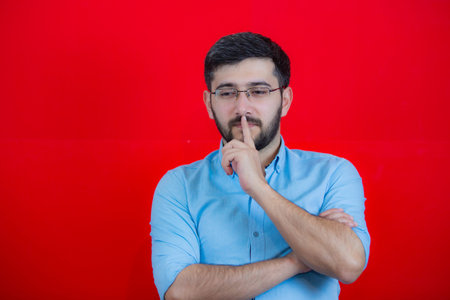 Young handsome man wearing casual t-shirt over red isolated background Thinking concentrated about doubt with finger on chin and looking up wonderingの写真素材